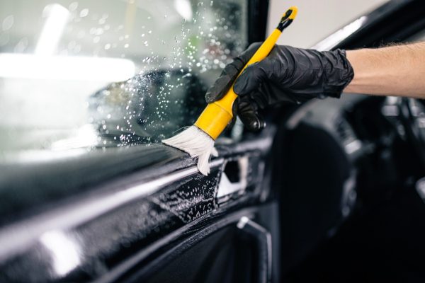 Car detailing. Professional car interior cleaning with the brush removing dust and dirt from the vehicle.