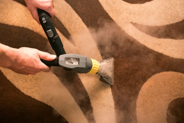 Le procédé de nettoyage des tapis à l'aide d'un aspirateur vapeur. Un employé d'une entreprise de nettoyage nettoie le tapis à la vapeur.